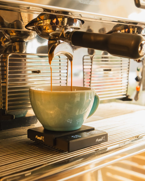 Espresso cayendo en una taza en la máquina de la cafetería